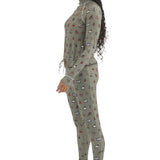Airblaster Women's Hoodless Ninja Suit 2025 - A woman with long dark braids wears a sage green ninja suit adorned with small, repeating images of various snowboard boots and bindings in red, white, black, and brown.