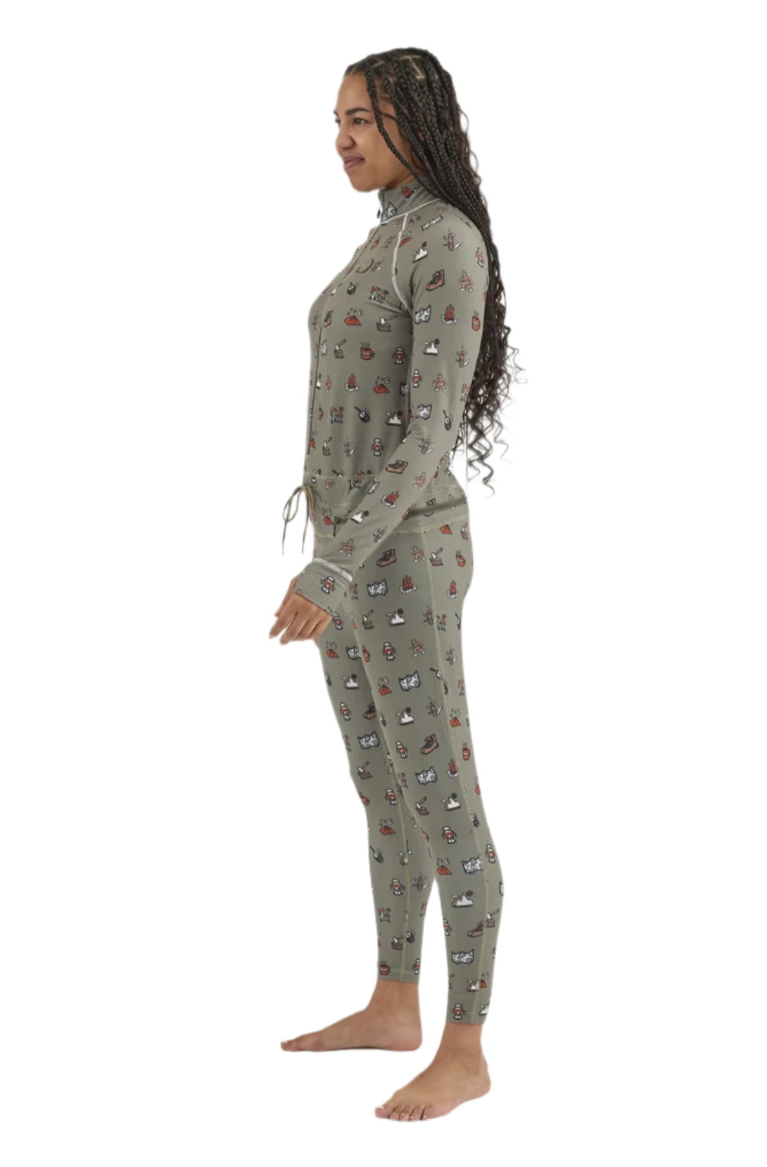 Airblaster Women's Hoodless Ninja Suit 2025 - A woman with long dark braids wears a sage green ninja suit adorned with small, repeating images of various snowboard boots and bindings in red, white, black, and brown.