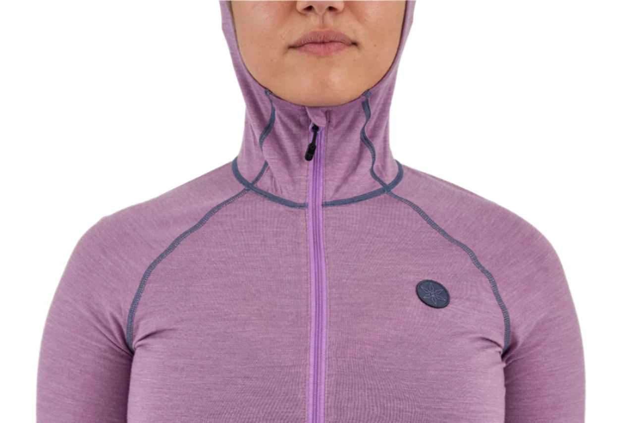 Airblaster Women's Merino Ninja Suit 2025 - A woman wearing a purple merino ninja suit with a hood, standing in front of a white background.