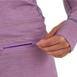 Airblaster Women's Merino Ninja Suit 2025 - A woman wearing a purple merino ninja suit with a zippered pocket on her hip.