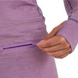Airblaster Women's Merino Ninja Suit 2025 - A woman wearing a purple merino ninja suit with a zippered pocket on her hip.