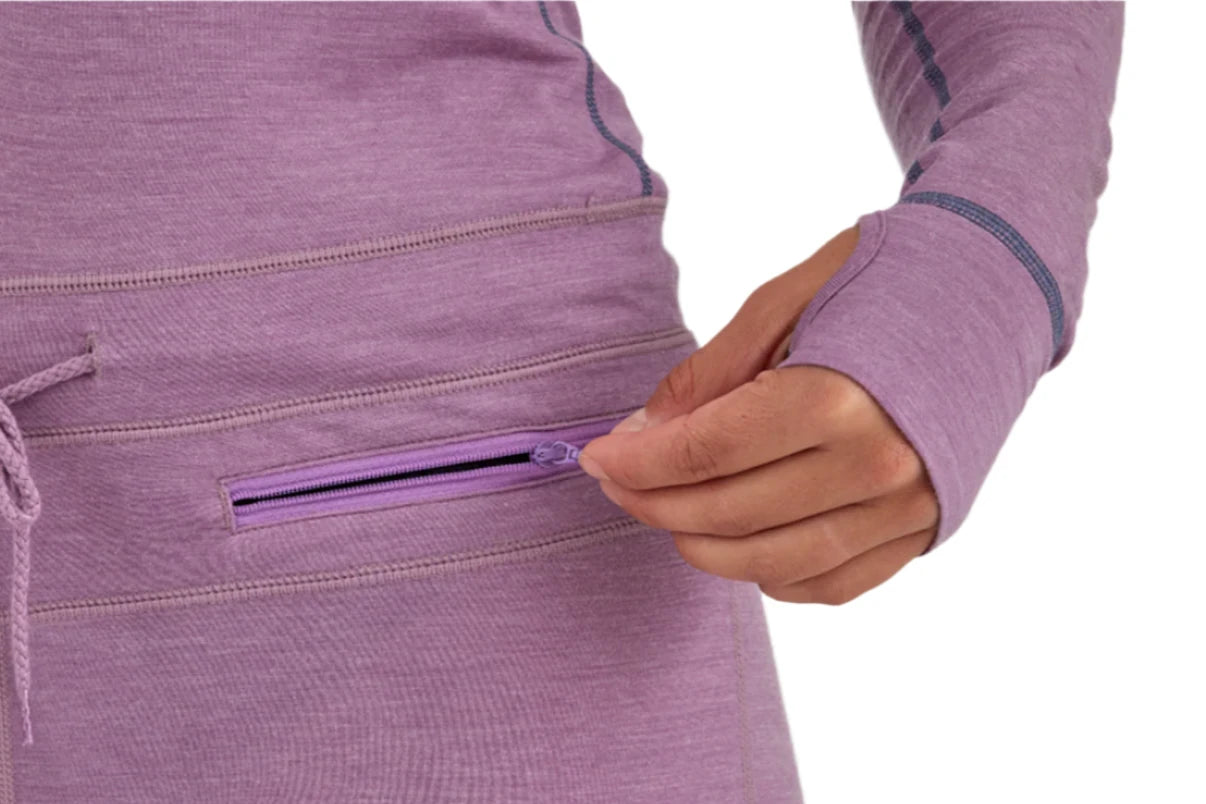 Airblaster Women's Merino Ninja Suit 2025 - A woman wearing a purple merino ninja suit with a zippered pocket on her hip.