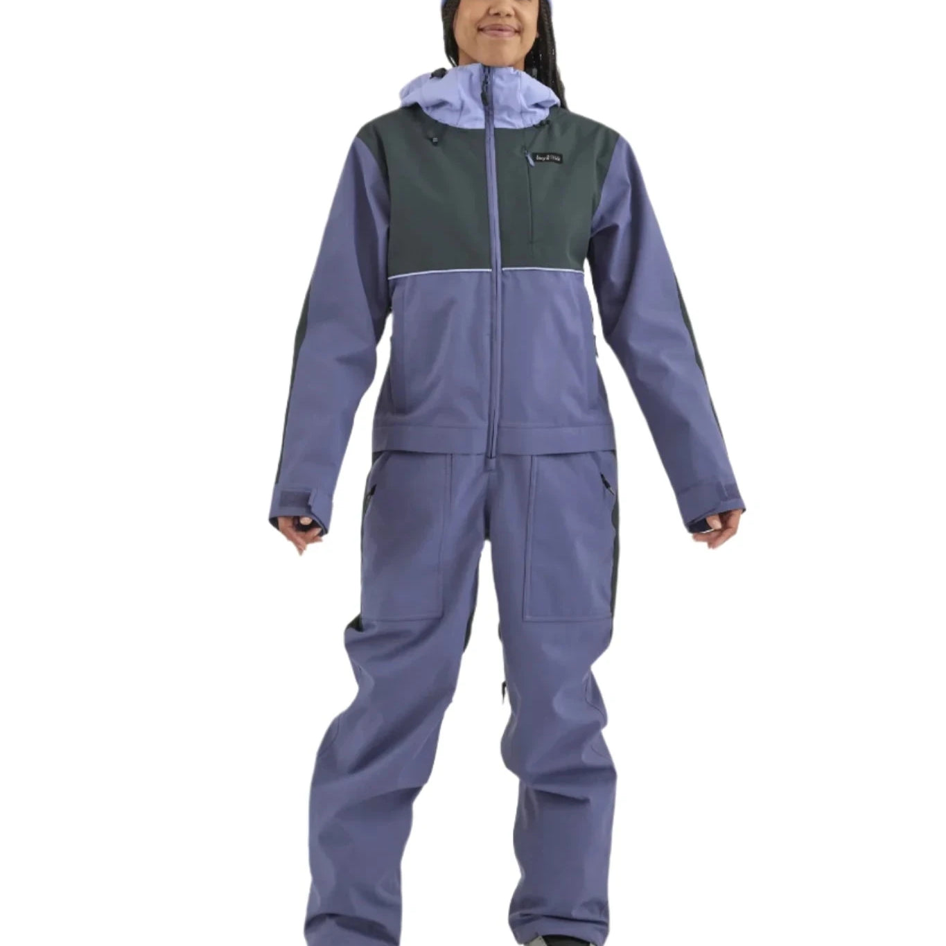 Airblaster Women's Stretch Freedom Suit 2025 - A woman wearing a blue and black snowsuit with a hood, standing in front of a white background.