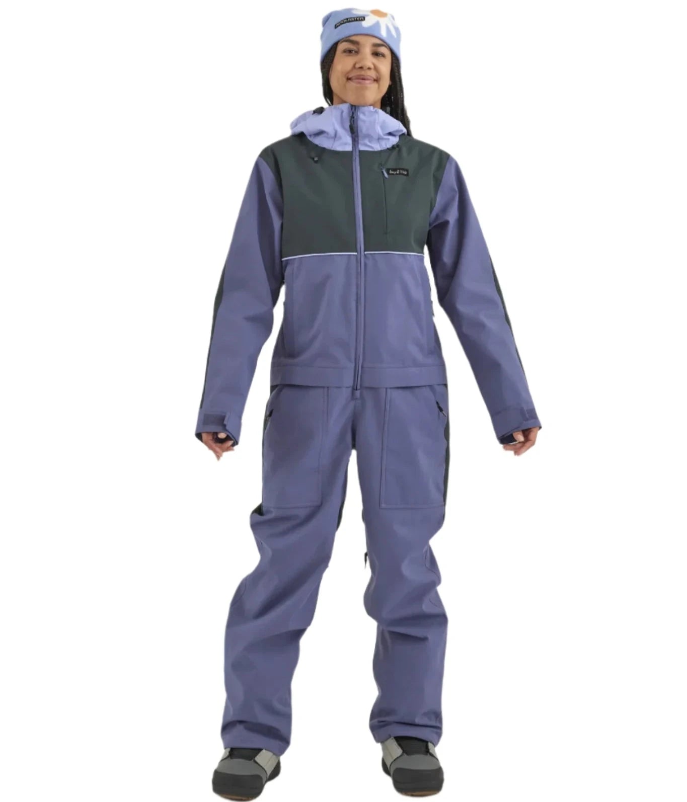 Airblaster Women's Stretch Freedom Suit 2025 - A woman wearing a blue and black snowsuit with a hood, standing in front of a white background.