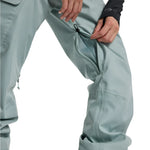 Burton Women's Gloria 2L Stretch Pants 2025 - A pair of light gray snow pants with a zippered pocket on the left thigh and a small black logo on the right leg.