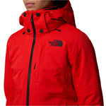 North Face Women's Lenado Insulated Jacket - A woman wearing a red jacket with black hardware and a hood, standing in front of a white background.
