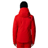 North Face Women's Lenado Insulated Jacket - A woman wearing a red jacket with black logo on the upper left side of the back, standing against a white background.