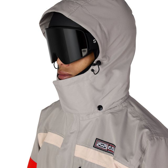 686 Logic jacket hood and chest patch, light gray with beige panels and red stripe detail.