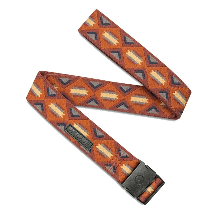 A fabric belt with a geometric pattern in shades of orange, brown, grey, and beige. The belt is folded in a crisscross pattern and has a rectangular plastic buckle. The word 'ARCADE' is embossed near the end.