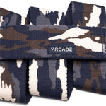 Close-up view of a camouflage-patterned belt in shades of blue, brown, and beige, showing a fabric tag with the word 'Arcade' stitched on it.