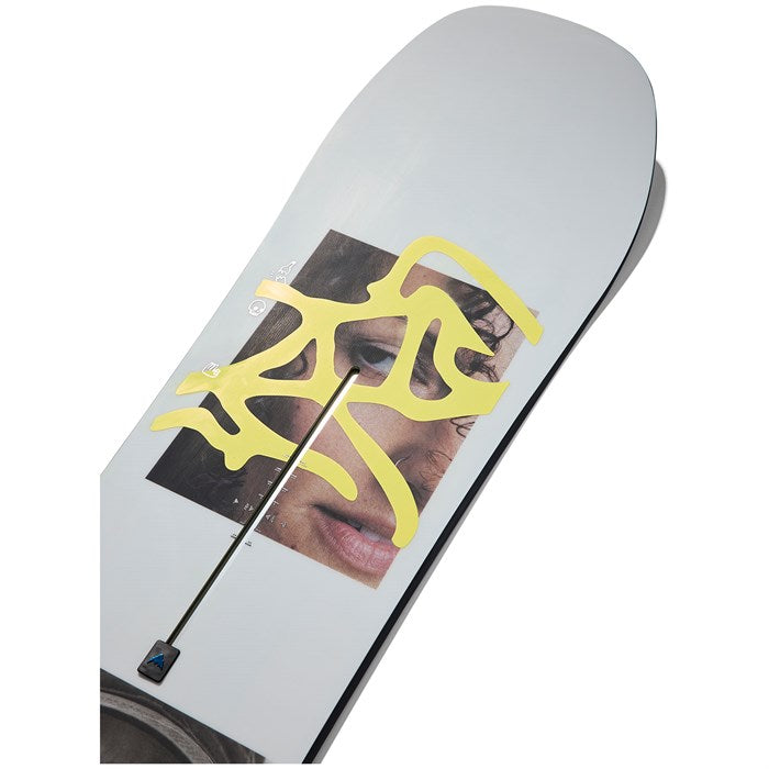 Burton Women's Story Board Snowboard - A white snowboard with a close-up photo of a woman's face on it, featuring yellow squiggly lines over her eyes and dark hair.