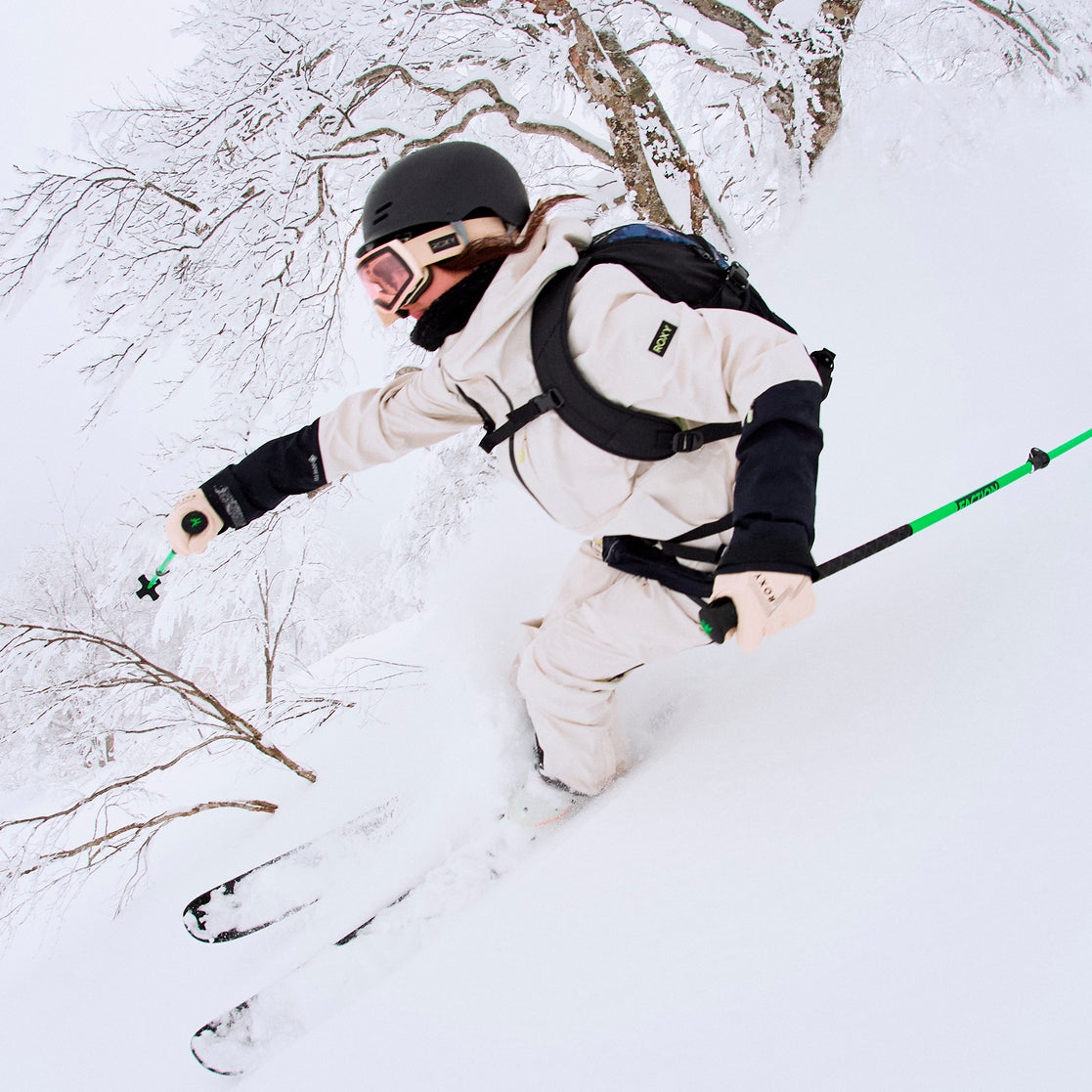 Roxy Women's Lunalite 3L GORE-TEX Jacket 2025 - A white jacket with black accents and a hood, worn by a woman skiing down a snowy slope.