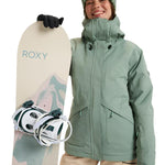 Roxy Women's Illumine Warmlink Jacket 2025 - A sage green jacket with a hood, worn by a model posing in front of a snowy mountain backdrop.