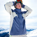 Roxy Women's Ritualized Insulated Jacket - A blue, white, and green ski jacket with a hood, worn by a woman in front of snowy mountains.