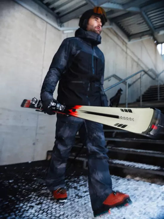 K2 Disruption MTI skis with MXC 12 bindings feature a black and red design against a snowy background.