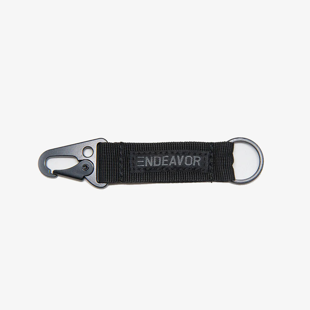 CLIP NYLON WEB KEYCHAIN 2023 - A black nylon keychain with a metal clip and ring, featuring a woven web design.