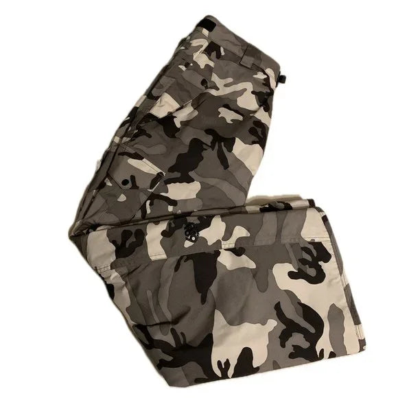 The 686 Defender Cargo Pants 2023 are depicted in a camouflage pattern with shades of brown and tan on a light beige background.