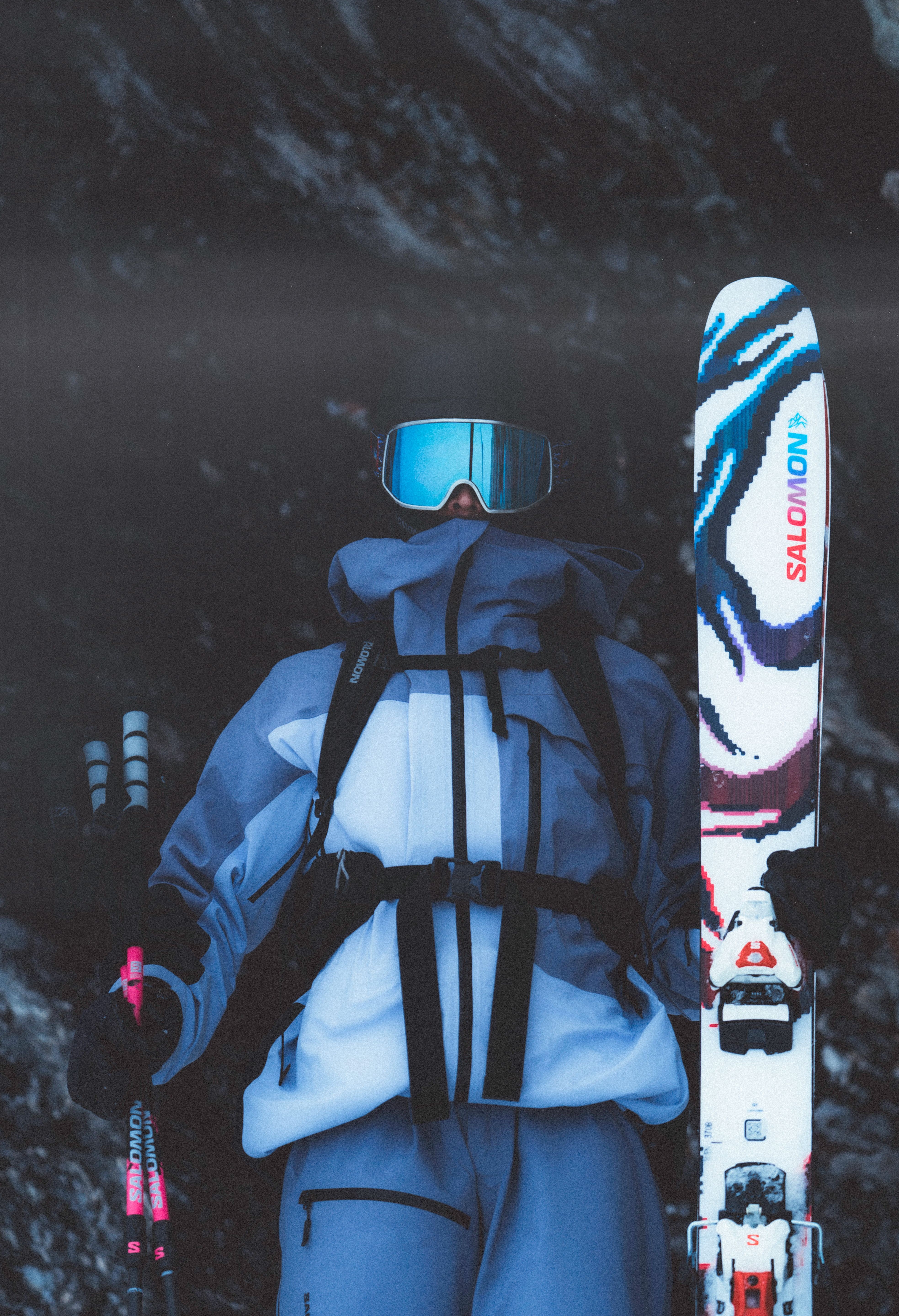 A person wearing a white jacket and blue pants, holding a pair of Salomon S/Lab QST Blank Skis 2026.