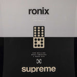 Ronix Supreme Wakeboard 2024 - A black wakeboard with a white logo and text on top, featuring a rider standing in front of it.