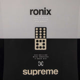 Ronix Supreme Wakeboard 2024 - A black wakeboard with a white logo and text on top, featuring a rider standing in front of it.
