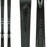 The image displays a pair of K2 Disruption 74 MTI skis with MXC 12 bindings for the year 2021. The skis are black and feature white lettering on their sides, indicating the brand and model information. They are positioned vertically in the frame, with the tips pointing upwards and the tails pointing downwards. The background is a neutral color, ensuring that the focus remains on the skis themselves.