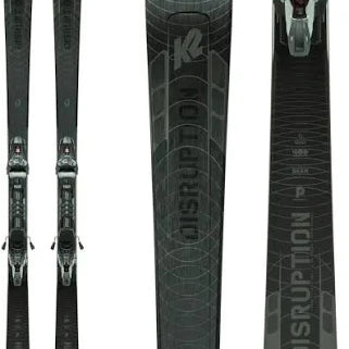 The image displays a pair of K2 Disruption 74 MTI skis with MXC 12 bindings for the year 2021. The skis are black and feature white lettering on their sides, indicating the brand and model information. They are positioned vertically in the frame, with the tips pointing upwards and the tails pointing downwards. The background is a neutral color, ensuring that the focus remains on the skis themselves.