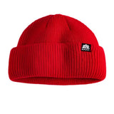 Autumn Shorty Double Roll Beanie 2025 - A red beanie with a black label featuring white text and a logo on the front.