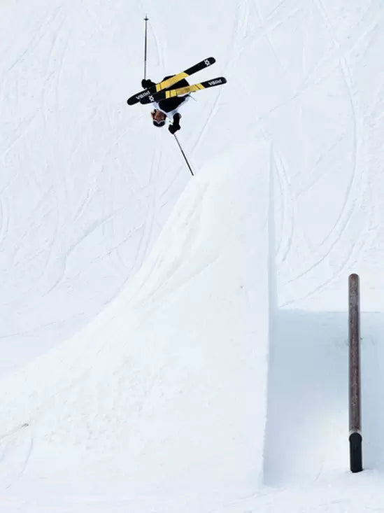 Volkl Revolt 96 Ski 2024 - A skier in a black and yellow jacket is seen from above, mid-air, with their skis parallel to the ground.