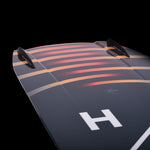 Hyperlite Baseline Wakeboard 2024 - A dark gray wakeboard with a white "H" logo on top and a red stripe along the bottom edge.