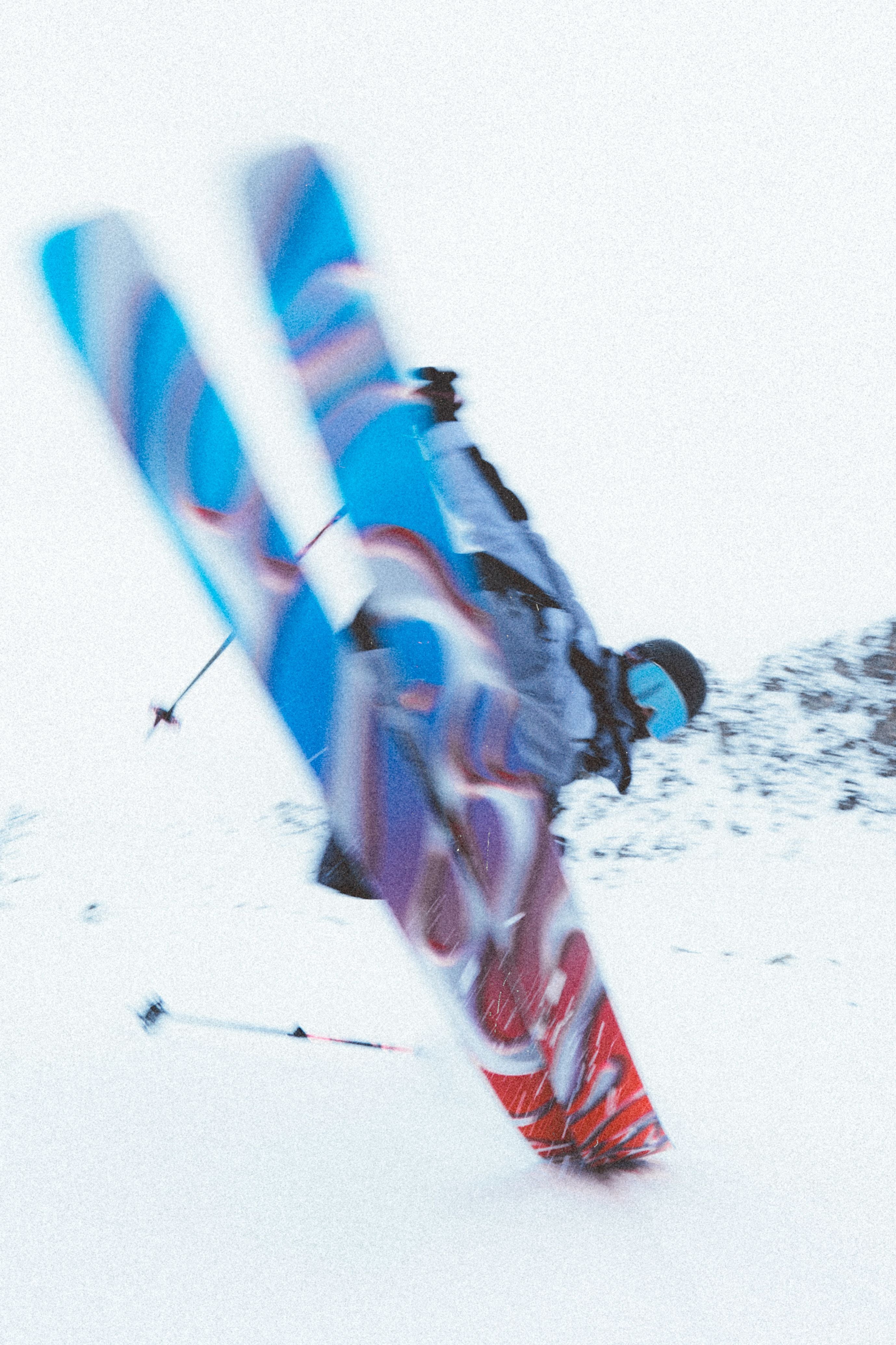 A person wearing a black jacket and skiing on snowy terrain. The skis are blue with red accents, and they have the brand name "Salomon S/Lab QST Blank Skis 2026" written on them.