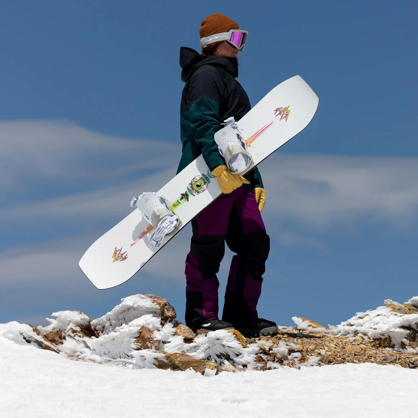 Jones Women's Tweaker Snowboard 2025 - A white snowboard with a pink and yellow logo on top of a mountain.