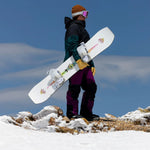 Jones Women's Tweaker Snowboard 2025 - A white snowboard with a pink and yellow logo on top of a mountain.