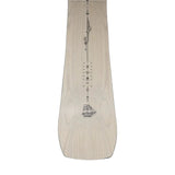 Jones Women's Flagship Snowboard 2025 - A light-colored snowboard with a black logo on top and a black stripe down the middle.