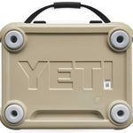 Yeti Roadie 24 Hard Cooler - A tan-colored cooler with a handle on top and four circular feet, featuring embossed lettering that reads "YETI" in large letters across its front.