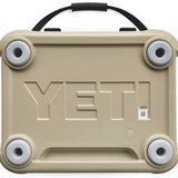 Yeti Roadie 24 Hard Cooler - A tan-colored cooler with a handle on top and four circular feet, featuring embossed lettering that reads "YETI" in large letters across its front.