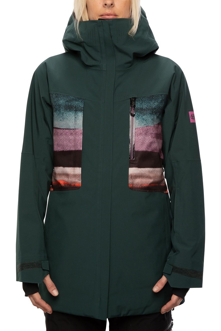The 686 GLCR Mantra Insulated Jacket, a dark green jacket with a multicolored panel on the chest and upper back, has an adjustable hood with a faux fur trim.