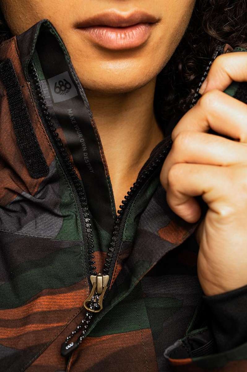 The 686 Willow insulated jacket is predominantly black with brown and green accents, featuring a zipper down the front.