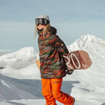The 686 brand's Women's GLCR Gore-Tex Willow insulated jacket is depicted in this image, showcasing a camouflage pattern with shades of green and orange.