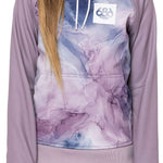 A young girl with long blonde hair wearing a purple and grey 686 hoodie with an insulated hood, smiling at the camera.