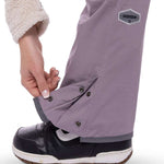 The 686 Black Magic insulated bib pants are primarily black with grey accents and have a zippered leg pocket on the right side.