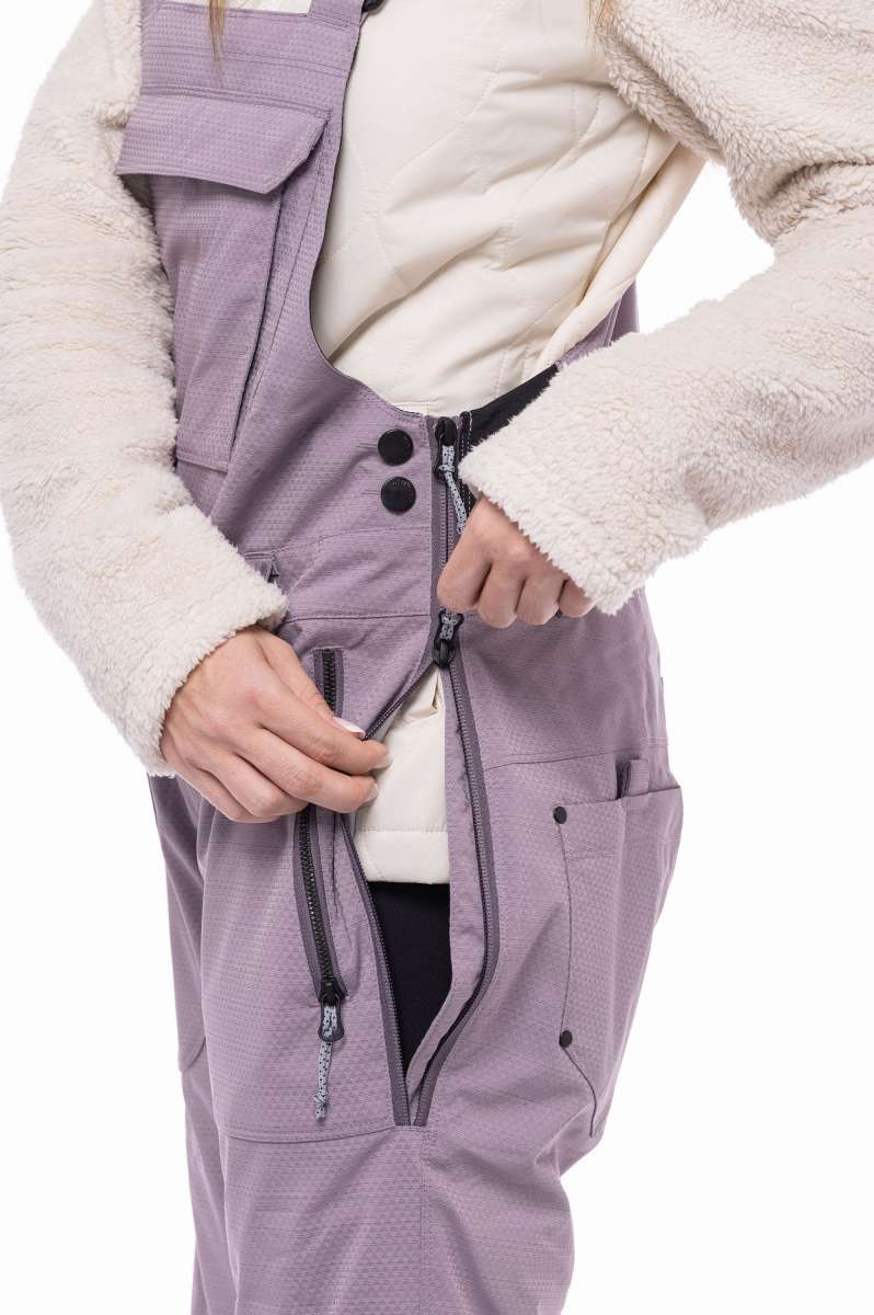 The 686 Ladies Black Magic Insulated Bib 2023 appears in an off-white color with black accents and a quilted pattern on the front.