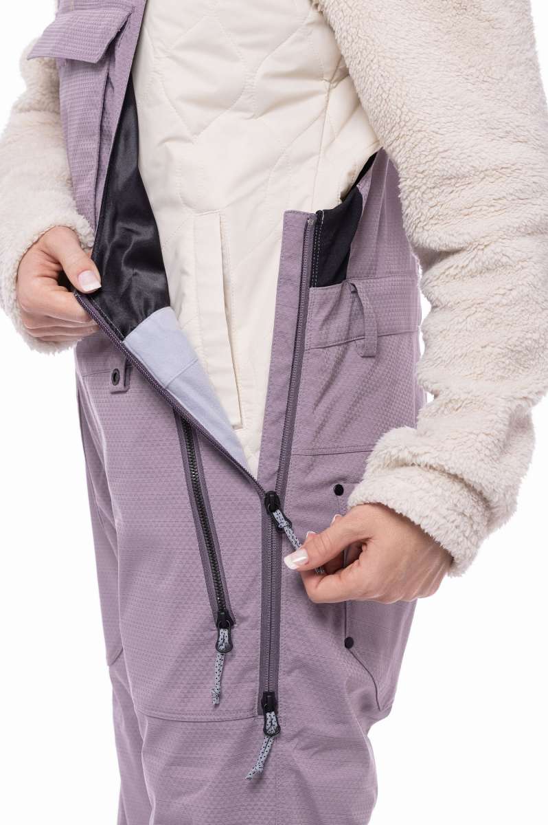 The 686 Ladies Black Magic Insulated Bib appears in a side view, showcasing a black color with a quilted pattern and a zippered fly.