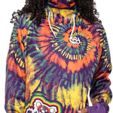 The 686 Ladies Bonded Fleece Pull Over Hoodie 2023 features a vibrant multicolored tie-dye pattern with an orange and yellow spiral design on the front.