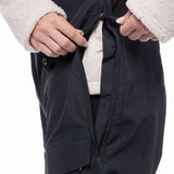 The 686 Women's Geode Thermagraph Bib 2023 has a black bib with an insulated cream-colored hood and white faux fur trim.