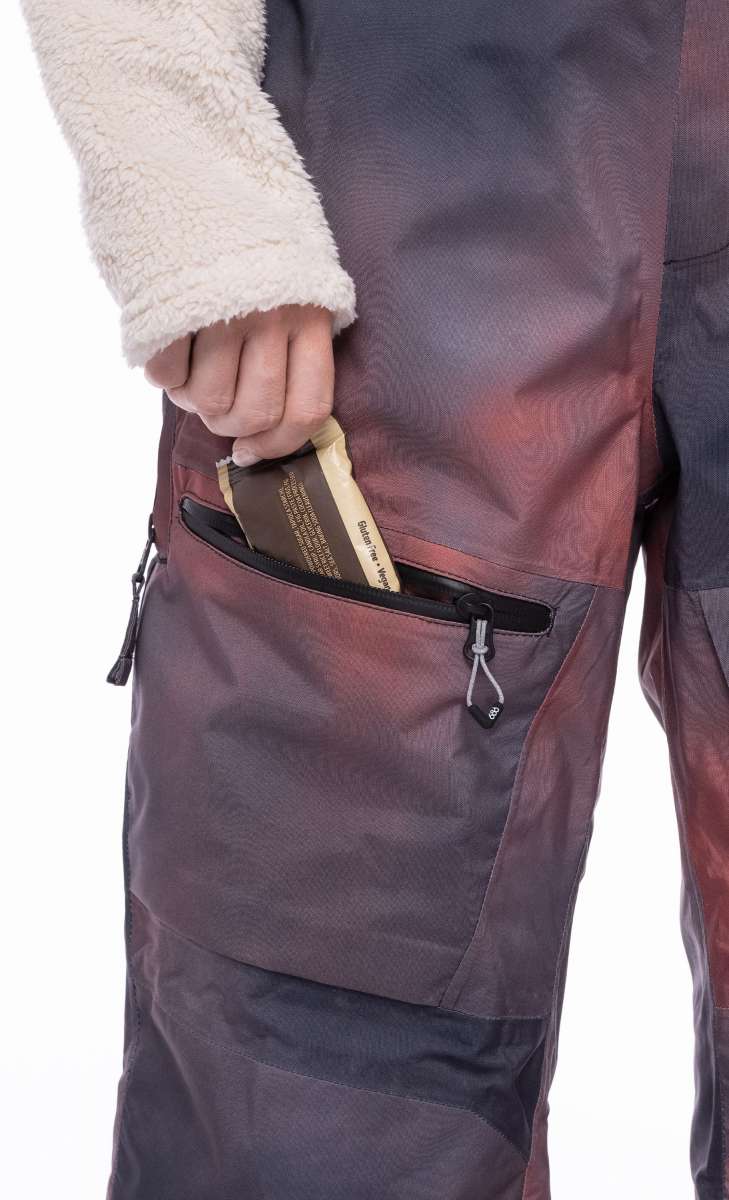 The 686 Women's Geode Thermagraph Bib 2023 is depicted in a side view, showcasing a dark brown color with an insulated hood.