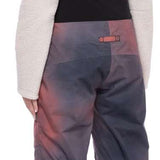 The 686 Women's Geode Thermagraph Bib 2023 has a purple and black color scheme with a distinctive geometric pattern on the front view.