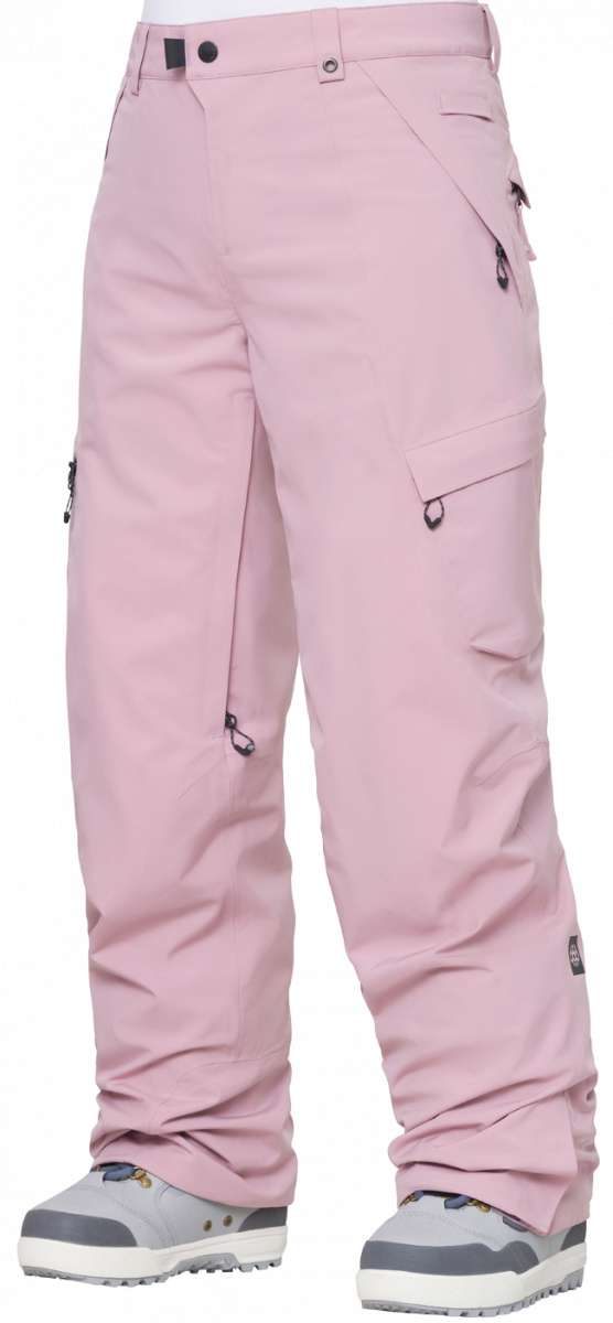 The 686 Women's Geode Thermagraph Pant 2024 is primarily light pink with black accents and a zippered pocket on the side.
