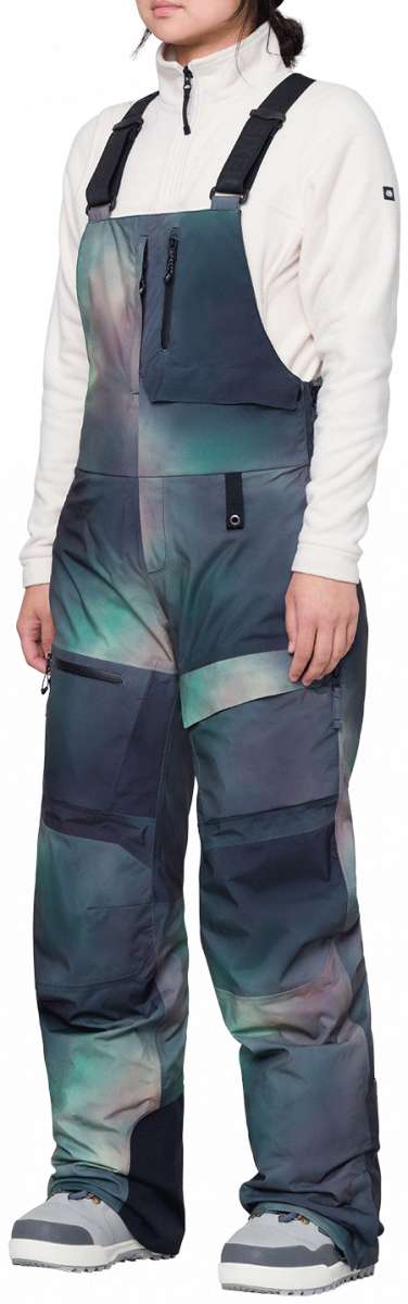 The 686 Women's Geodge Thermagraph Bib 2024 is depicted in a front view with a blue and green tie-dye pattern.