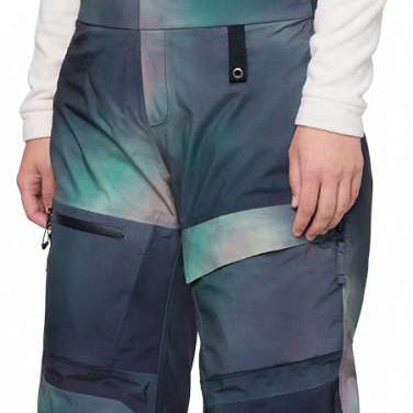 The 686 Women's Geodge Thermagraph Bib 2024 is depicted in a front view with a blue and green tie-dye pattern.