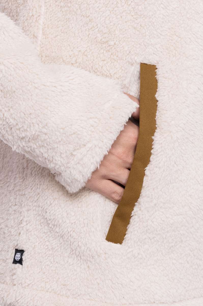 The 686 Ladies Hemlock Fleece Hoodie 2023 is cream-colored with an insulated hood and a brown drawstring.